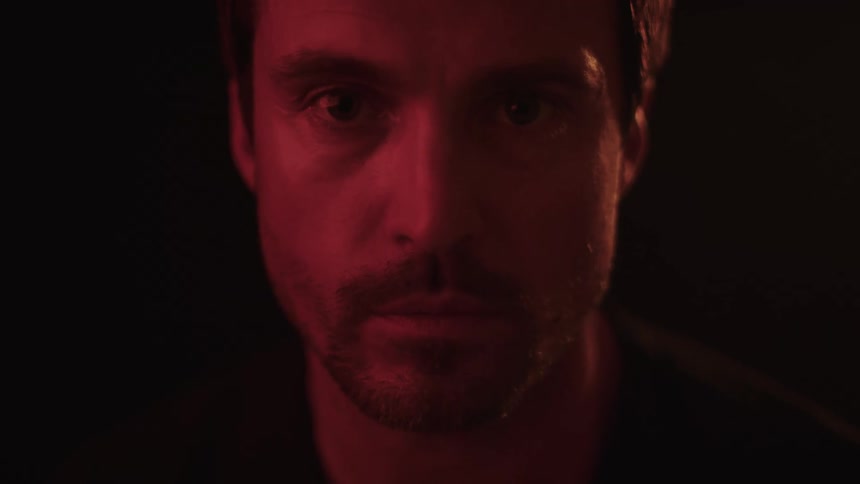 Portrait of a bearded man looking straight ahead in a dark room