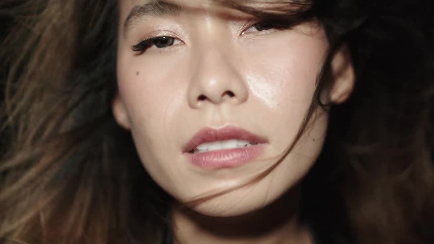 A young woman with long hair looks forward with an intense slightly partedlip expression