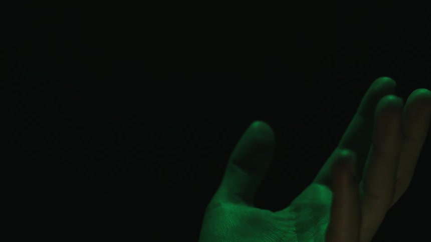 Closeup of a male hand rotating back and forth while illuminated by changing colors of lights