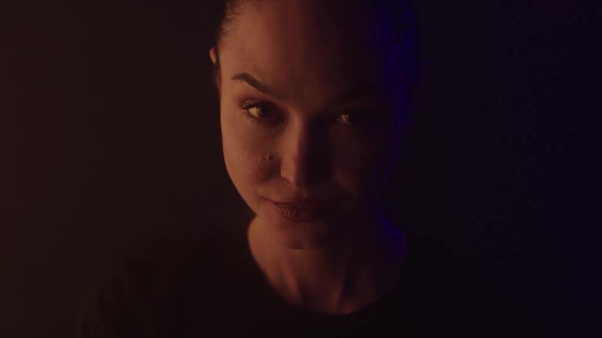 The woman turns and smiles in the dark