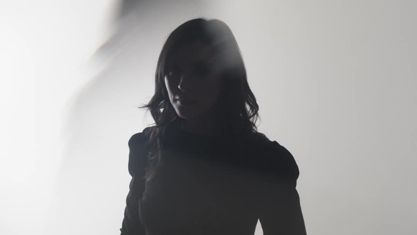 Female silhouette partially lit against a white background