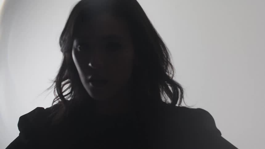 Woman in silhouette appears against a bright white background