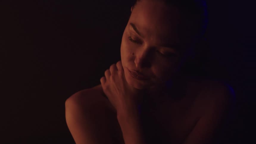 Woman lit in warm and dark tones with an intense expression