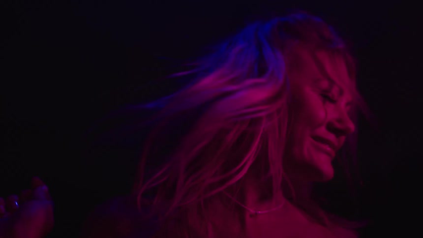 Smiling woman dances under purple and pink neon lights