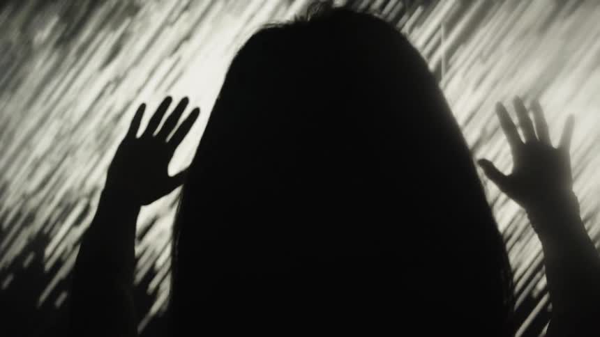 The silhouette of a person with raised hands appears against a bright streaked light background