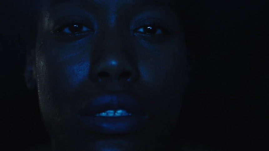 Face lit by blue light highlights an intense expression in the dark