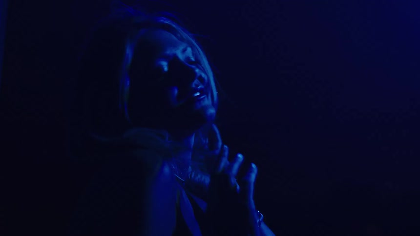 Woman dances under blue lighting in a dark setting