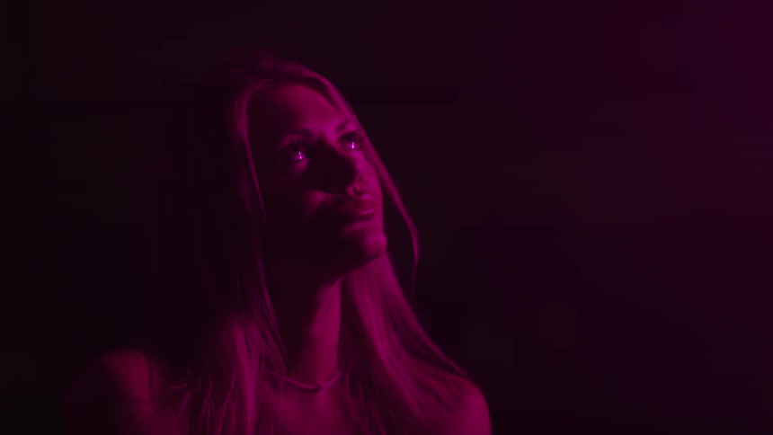 The woman is looking up under the red light
