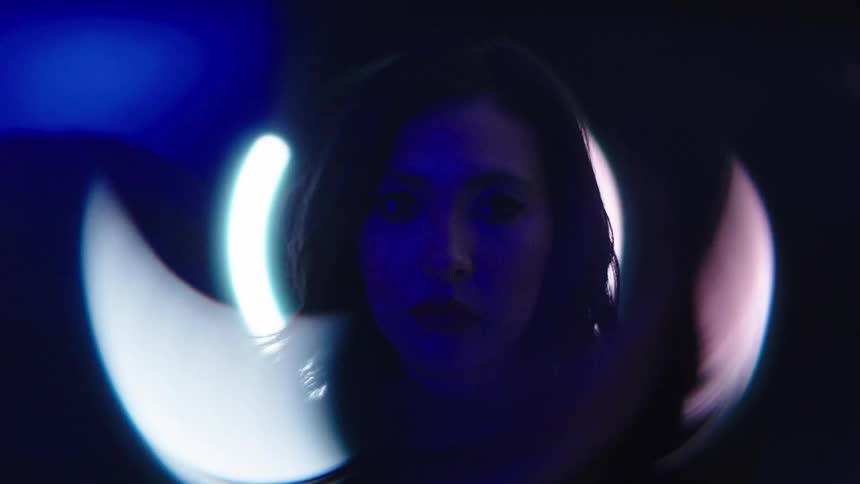 Female face partially lit by circular reflections of blue light