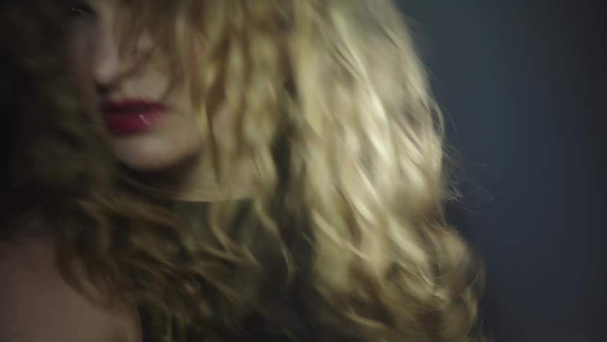 A woman with long wavy hair is partially visible in dim light is dancing under strobe fast lighting