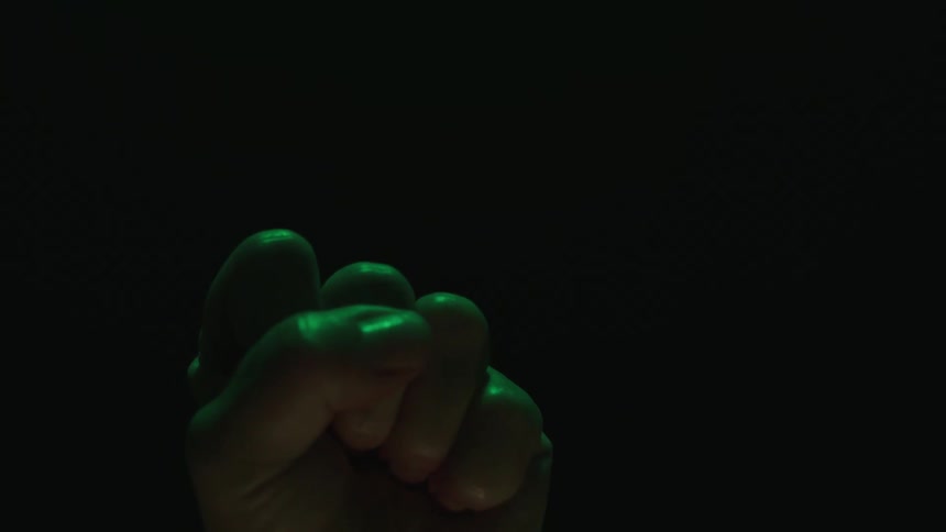 Hand opening and closing against a dark background
