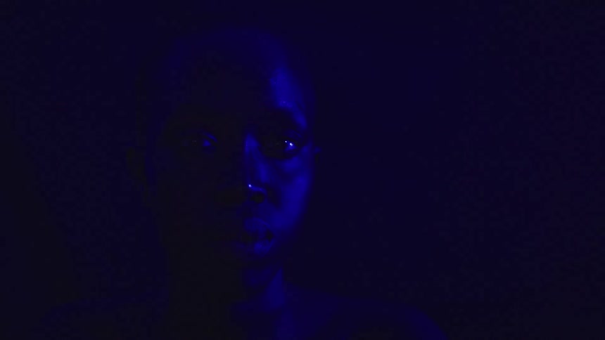 Closeup face lit by intense blue light in the dark