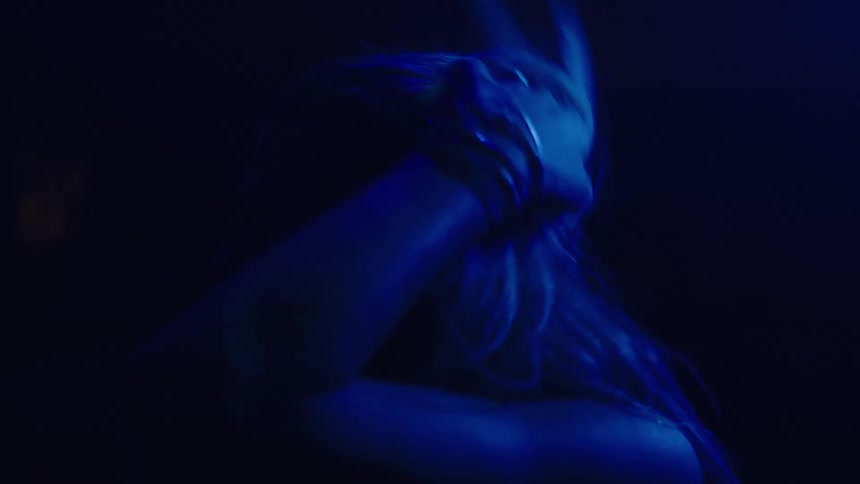 A woman is dancing and smiling in the dark