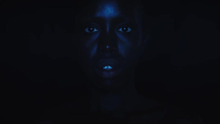 Face illuminated in blue tones emerging from the darkness
