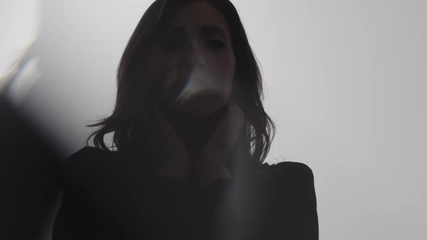 Emale silhouette with hands on head against bright background