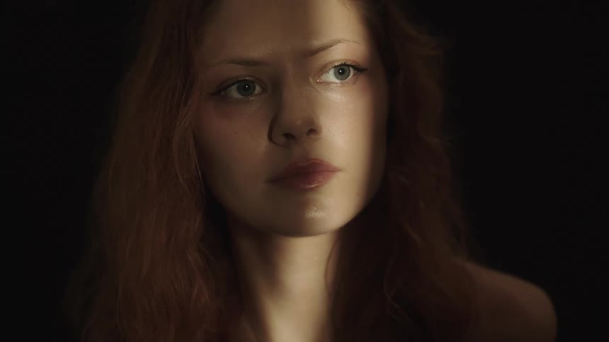 The woman looks towards the light in the dark room