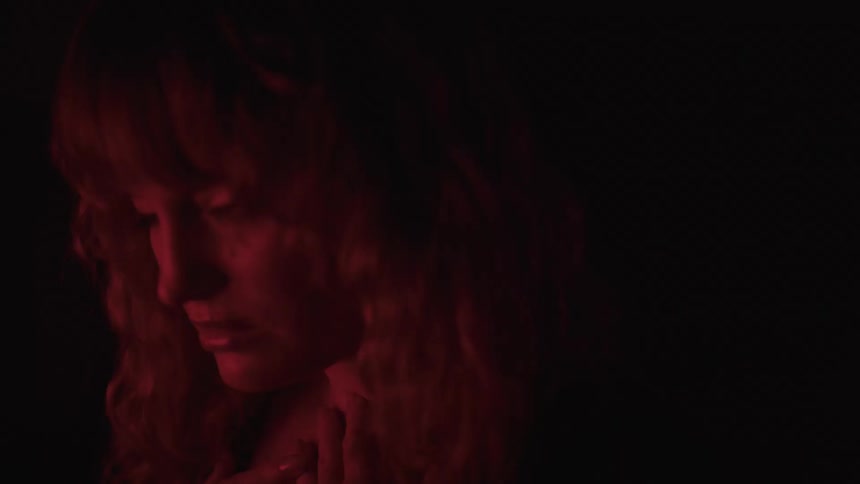 Redheaded woman with long hair briefly turns her head to the side to stare before facing upwards