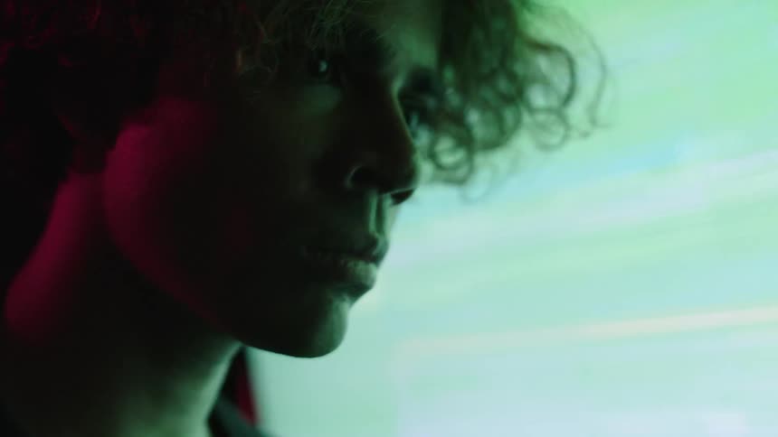 Young mans face lit by light in front of a screen