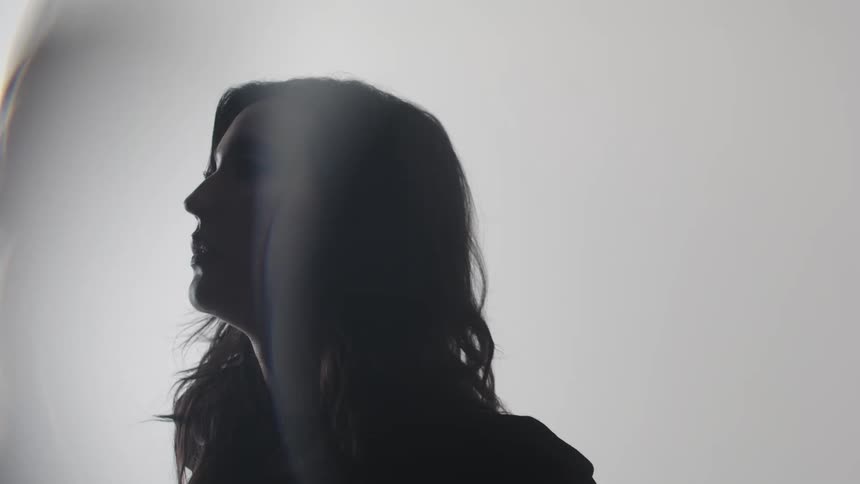 A young woman in a room expresses sadness and frustration by holding her head with both hands