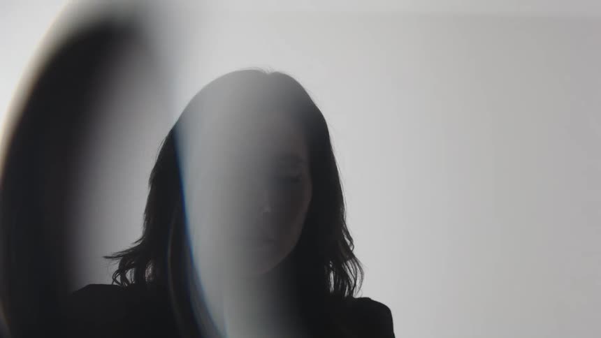 Female figure in silhouette partially lit by a beam of light