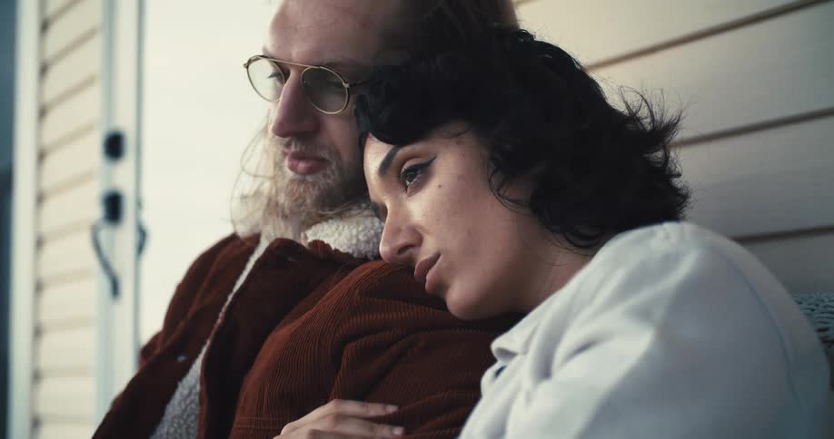 A woman rests her head on a man shoulder in an intimate moment
