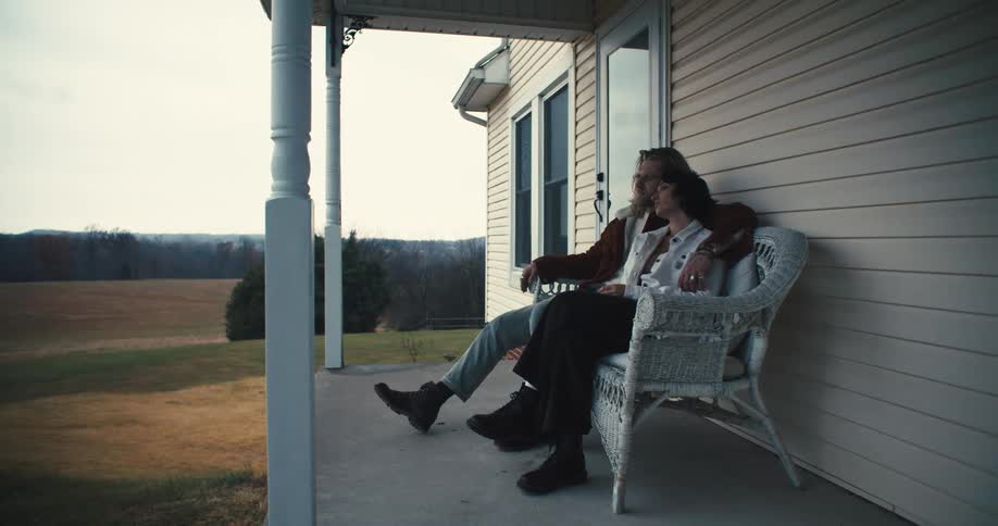 A couple sit together on the farmhouse porch