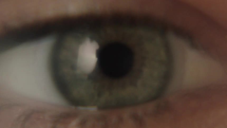 A closeup of a human eye shows the iris and pupil in detail