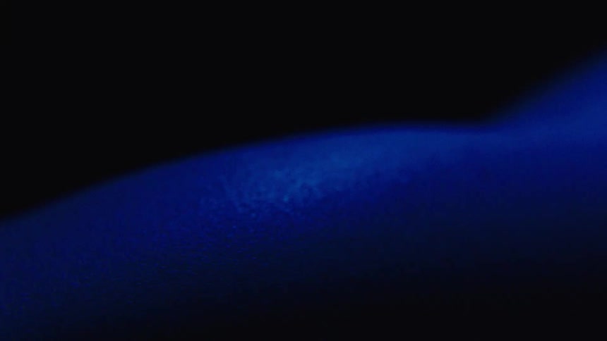 Part of a human body moving in the dark with blue light bathing part of the skin