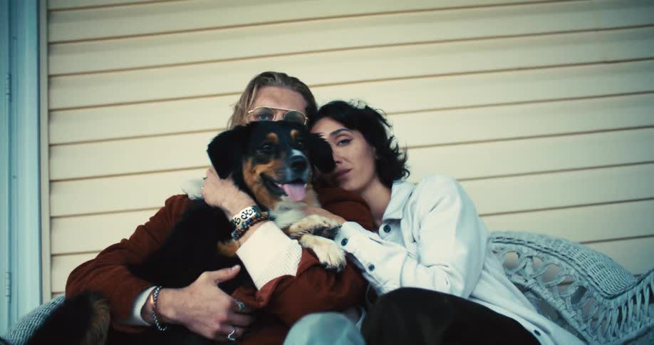 A couple hold their dog while sitting on the porch