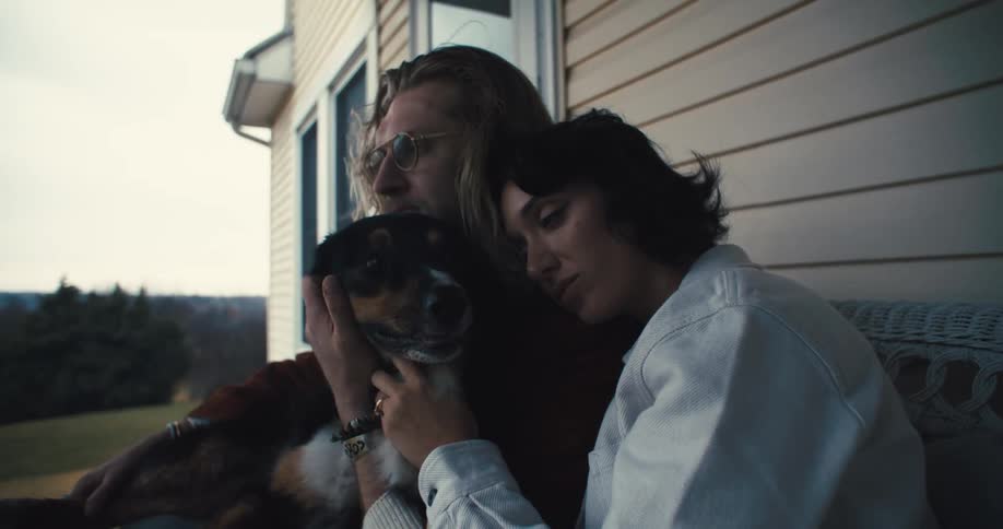 Couple sitting on the porch hugs a mediumsized dog