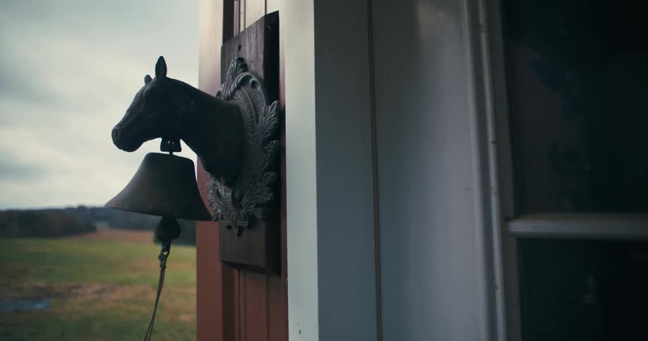 The woman rings the bell on the farm house