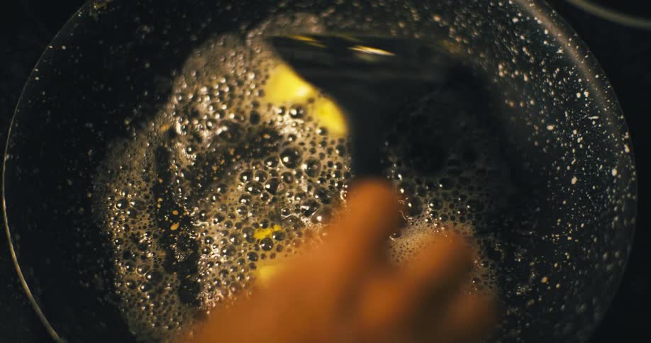 Butter is being stirred as it bubbles in a pan