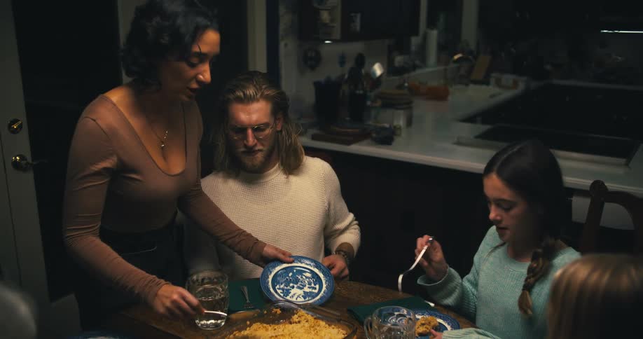A family sits together at the dinner table while food is being served