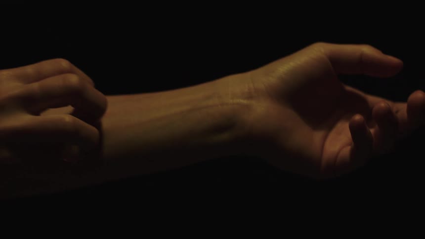 A woman gently scratches her own forearm with her other hand