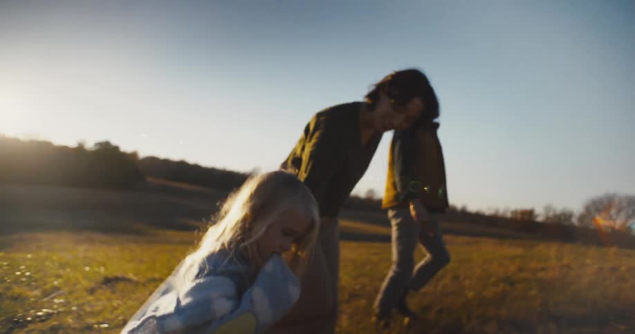A father mother and child walk up a hill on a grassland at midday