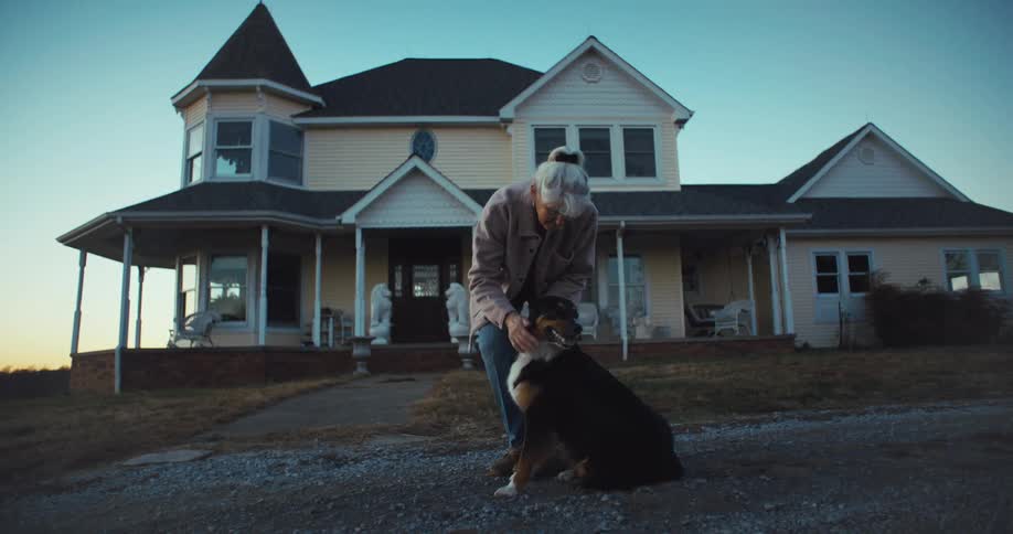 A woman is petting her dog by the home