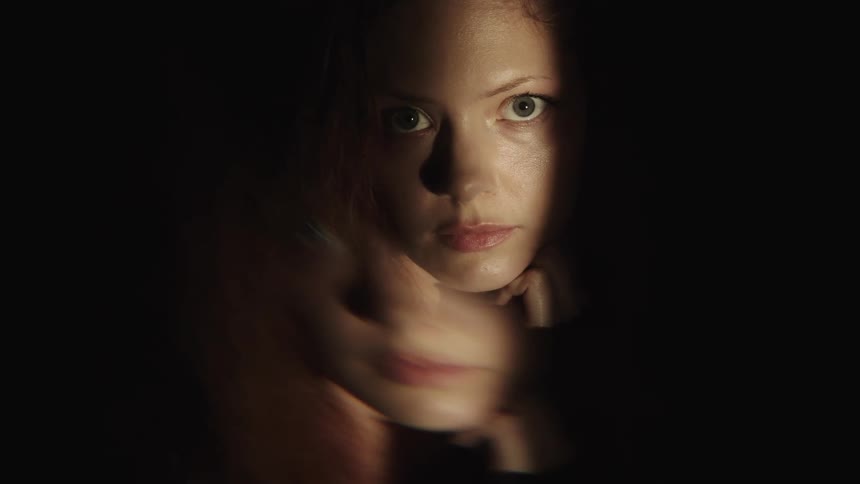 The woman looks up in the dark