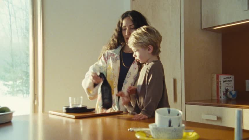 Woman opens a package in the kitchen next to her son