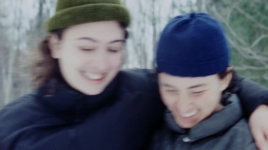 A lesbian couple kisses outdoors in the snow