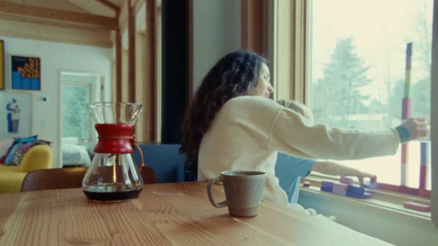 A mother plays with her young son by the window at home