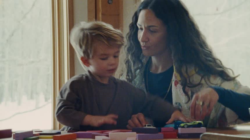 Woman plays with a child arranging colorful pieces on the table