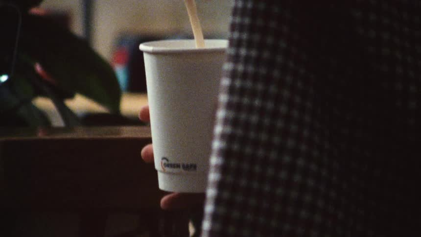 A barista pours coffee into a cup at a cafe