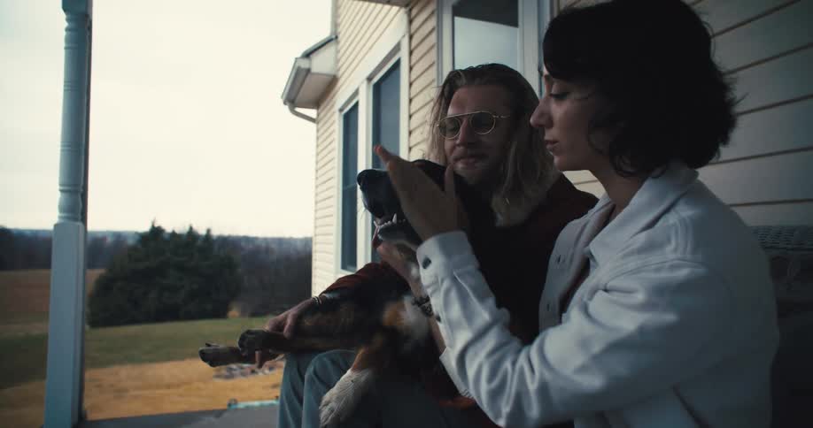 Couple sitting on the porch petting a dog