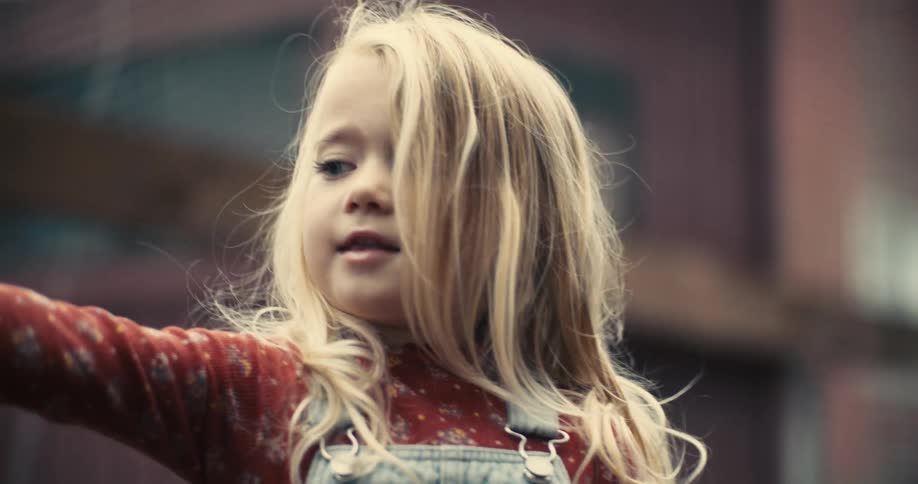 A very close view of a child with light colored hair and a red shirt with a white pattern shows them with an open mouth and an excited expression