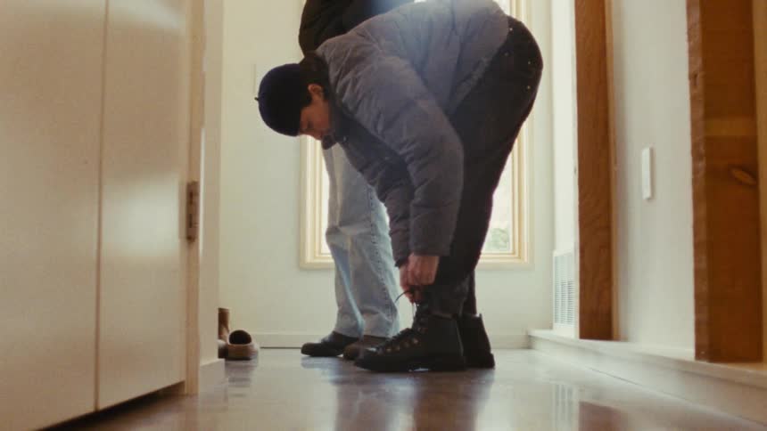 Person tying boots in the hallway of a house