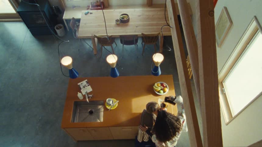 Overhead view of a bright kitchen with a central island where a woman pours a drink