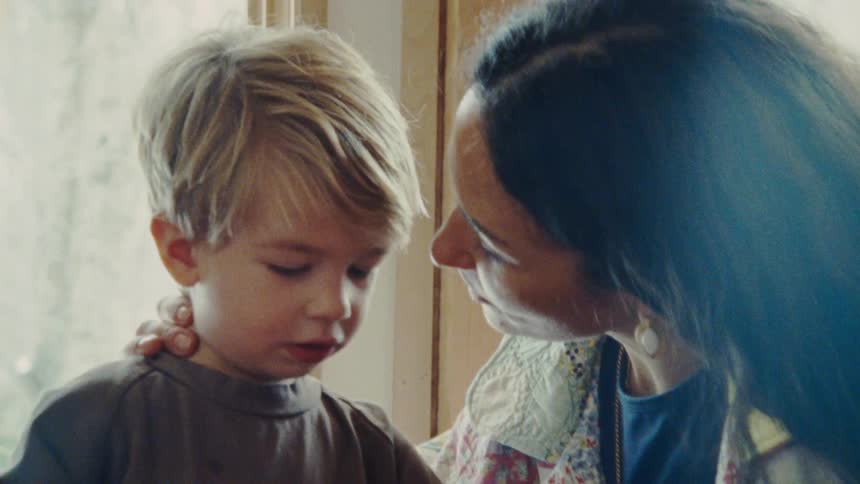 Woman kissing the forehead of a blonde child
