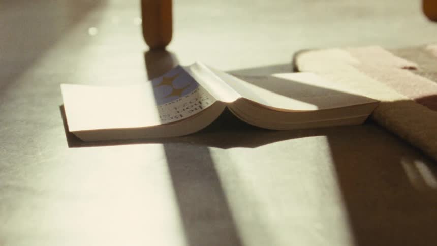 Hand placed open book on the floor illuminated by sunlight