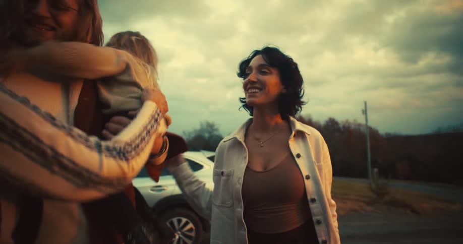 The video shows a woman with dark hair and a light shirt walking away from a car she turns and smiles at the camera revealing a confident and happy expression