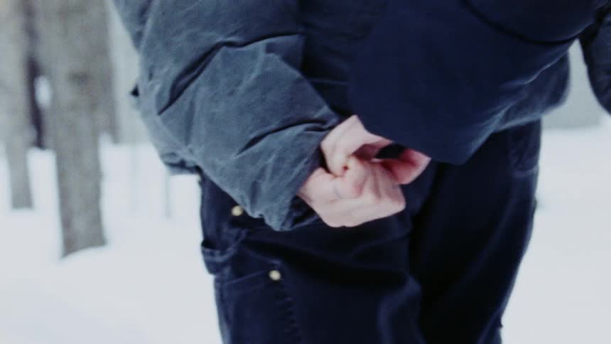 Two people hold hands while walking together in a snowy outdoor setting